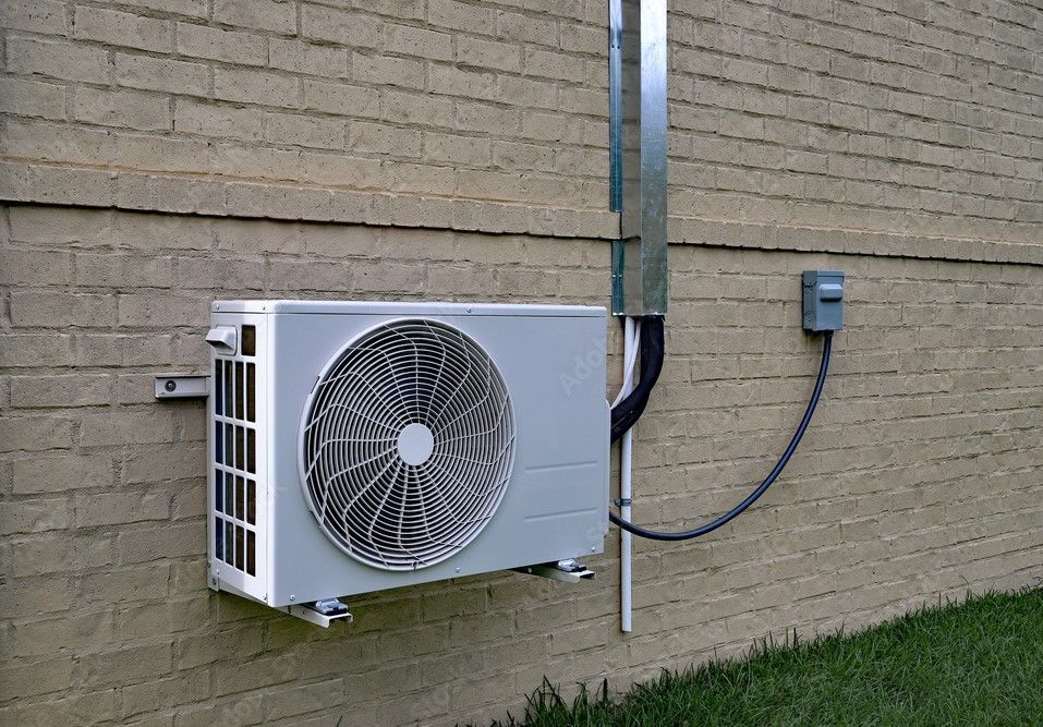 A white air conditioner is mounted on the side of a brick building.