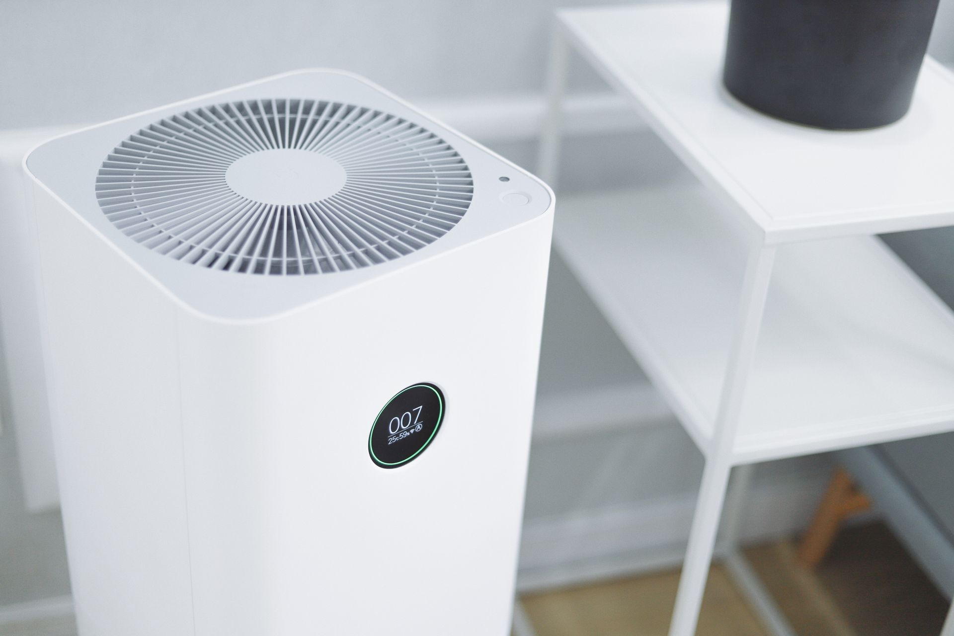 A white air purifier is sitting on top of a white table.