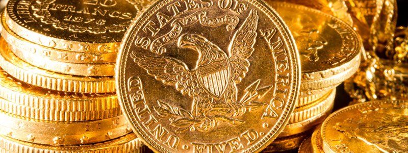 A gold coin with an eagle on it is sitting on top of a pile of gold coins.