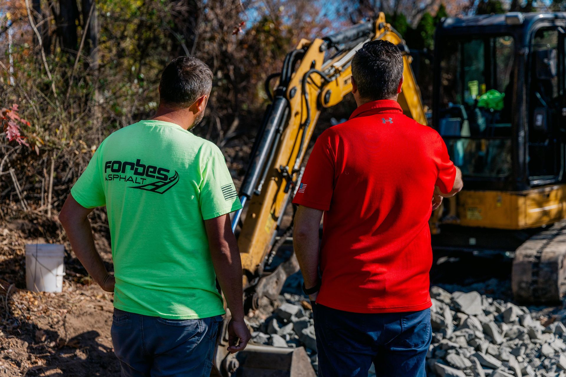 Two men are standing next to a bulldozer on a dirt road.