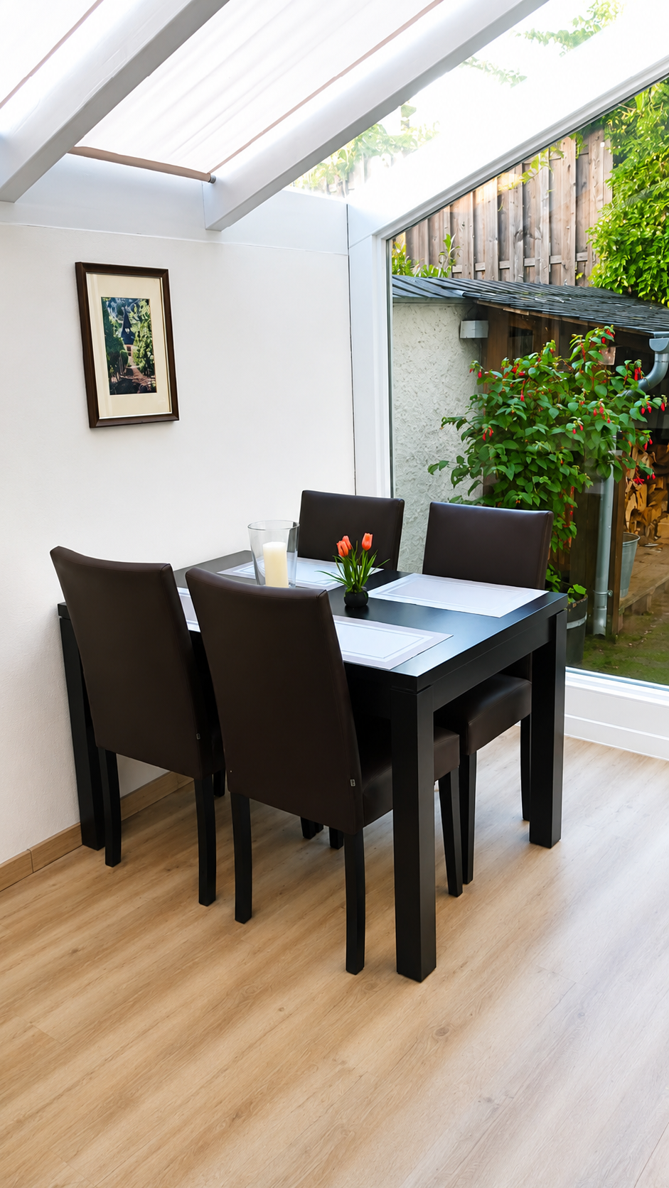 Moderner Essbereich mit schwarzem Tisch und Stühlen neben einem hellen Fenster und Blick ins Grüne