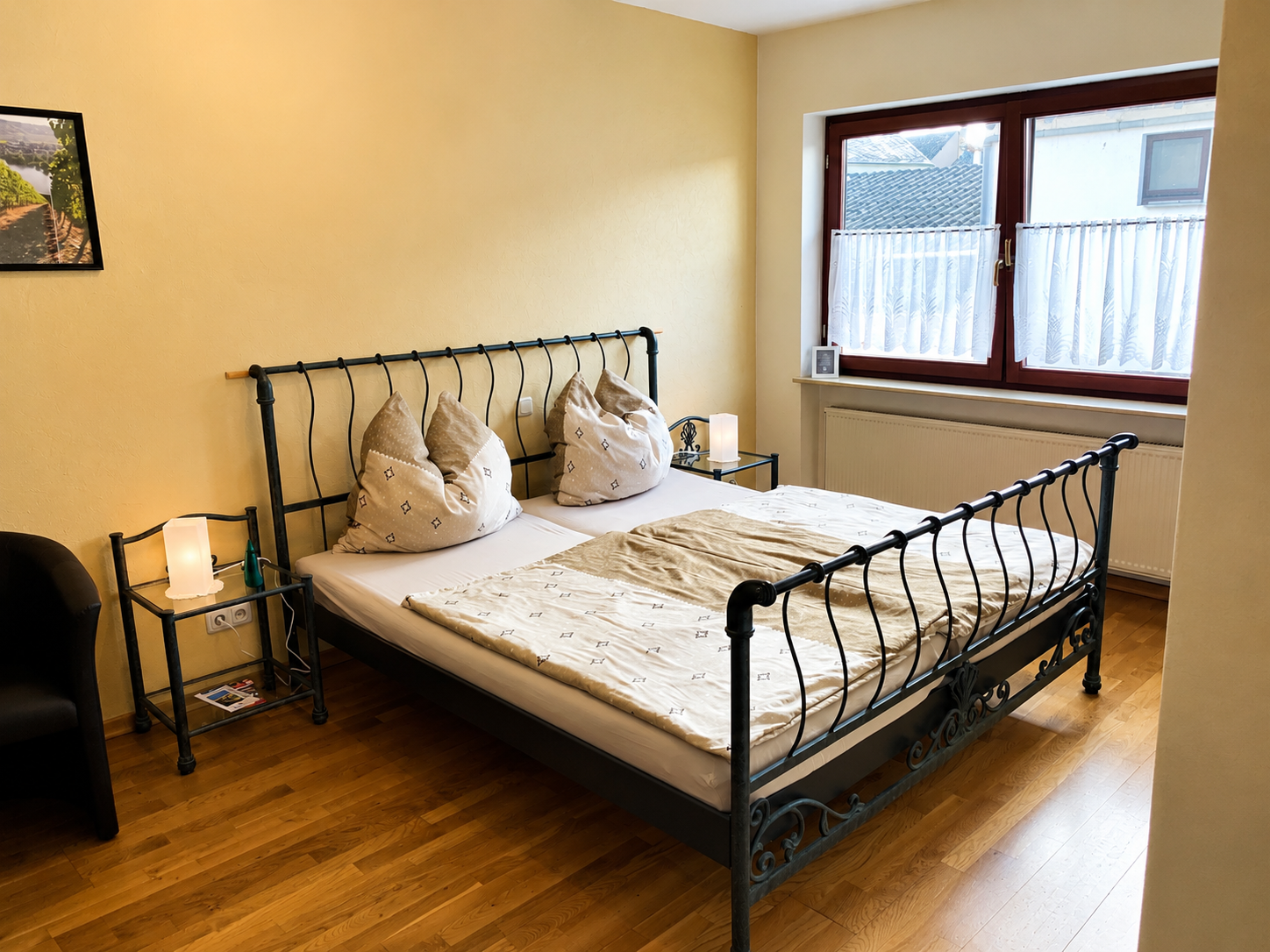 Ein ordentlich gemachtes Bett in einem hellen Schlafzimmer mit Holzboden und einem großen Fenster