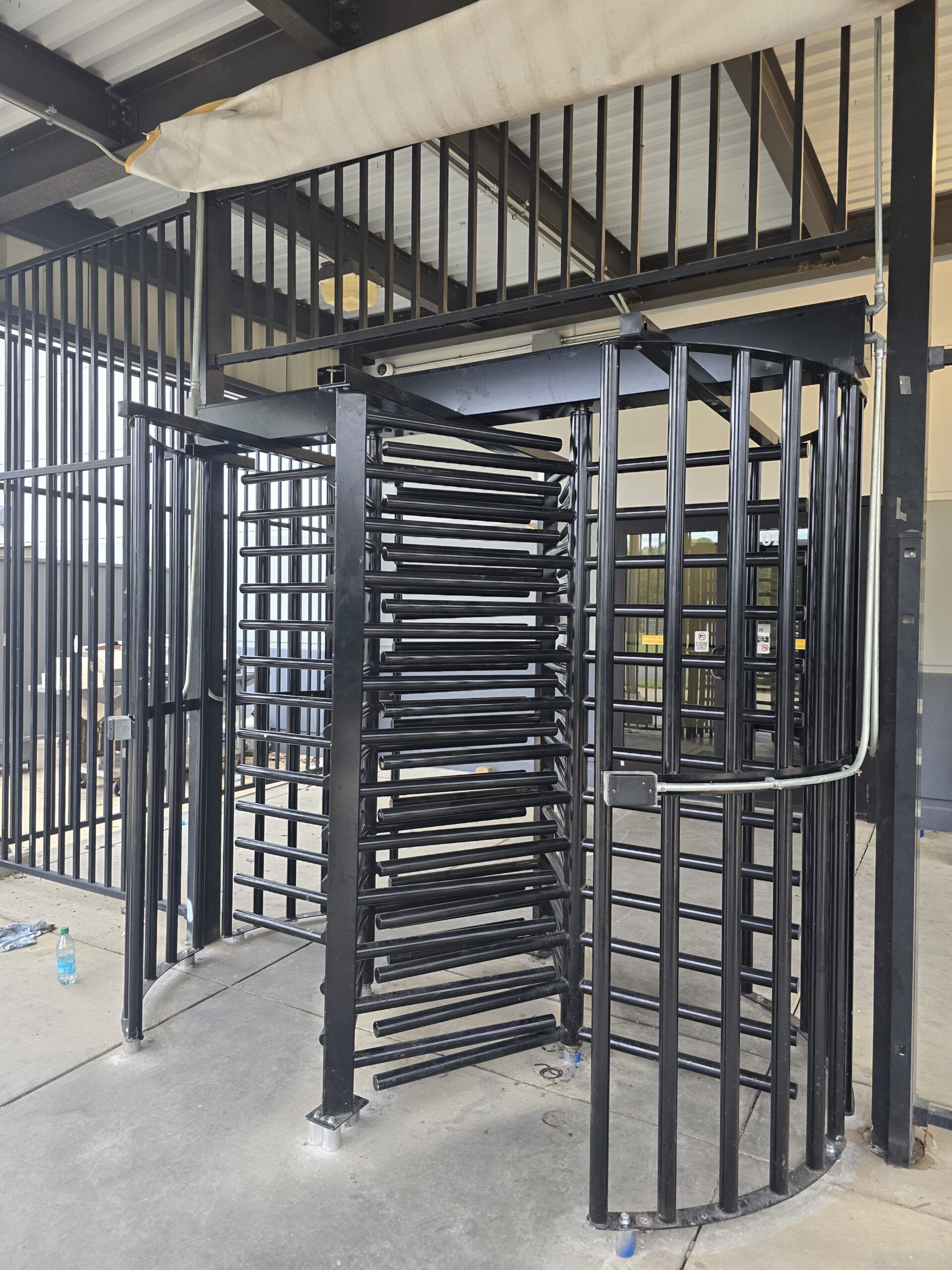 Black metal turnstile in an enclosed area with vertical bars.