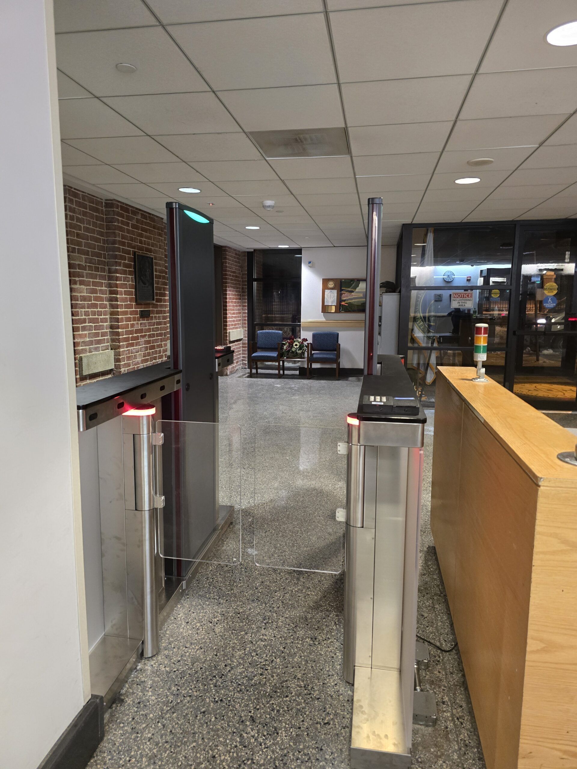 Turnstile entrance in a building with a red light, leading to a hallway.