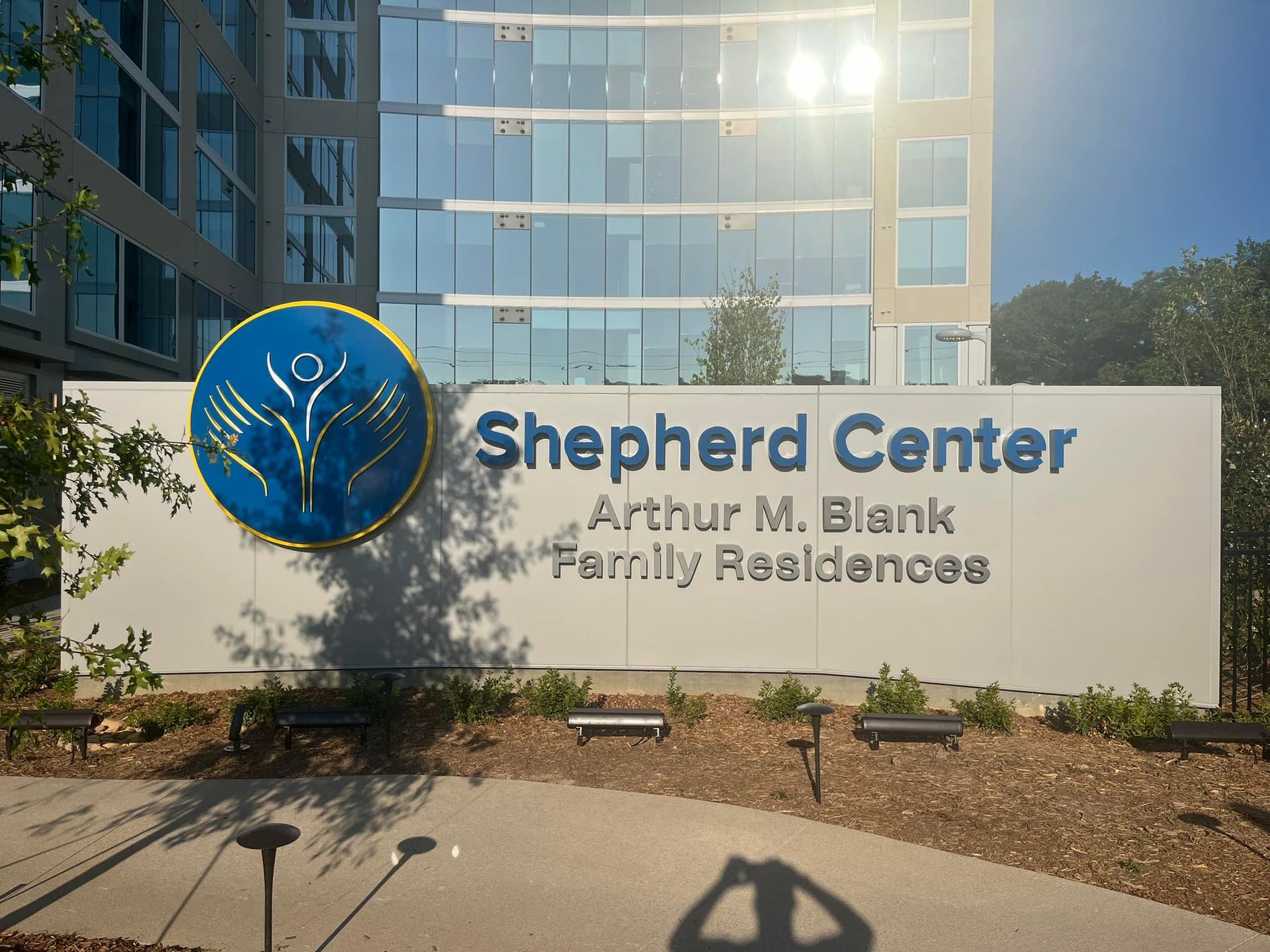 Sign for Shepherd Center Arthur M. Blank Family Residences, with a blue and gold logo, in front of a modern building.
