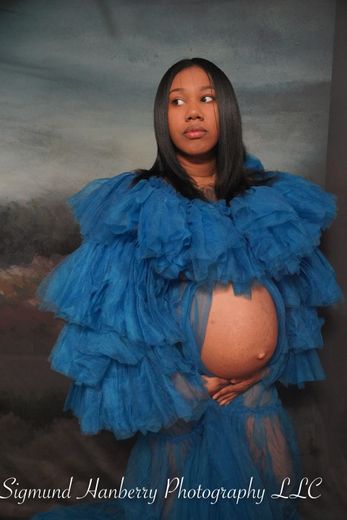 A pregnant woman is wearing a blue tulle dress