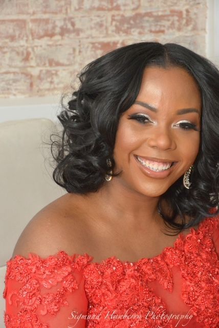 A woman in a red off the shoulder dress is smiling