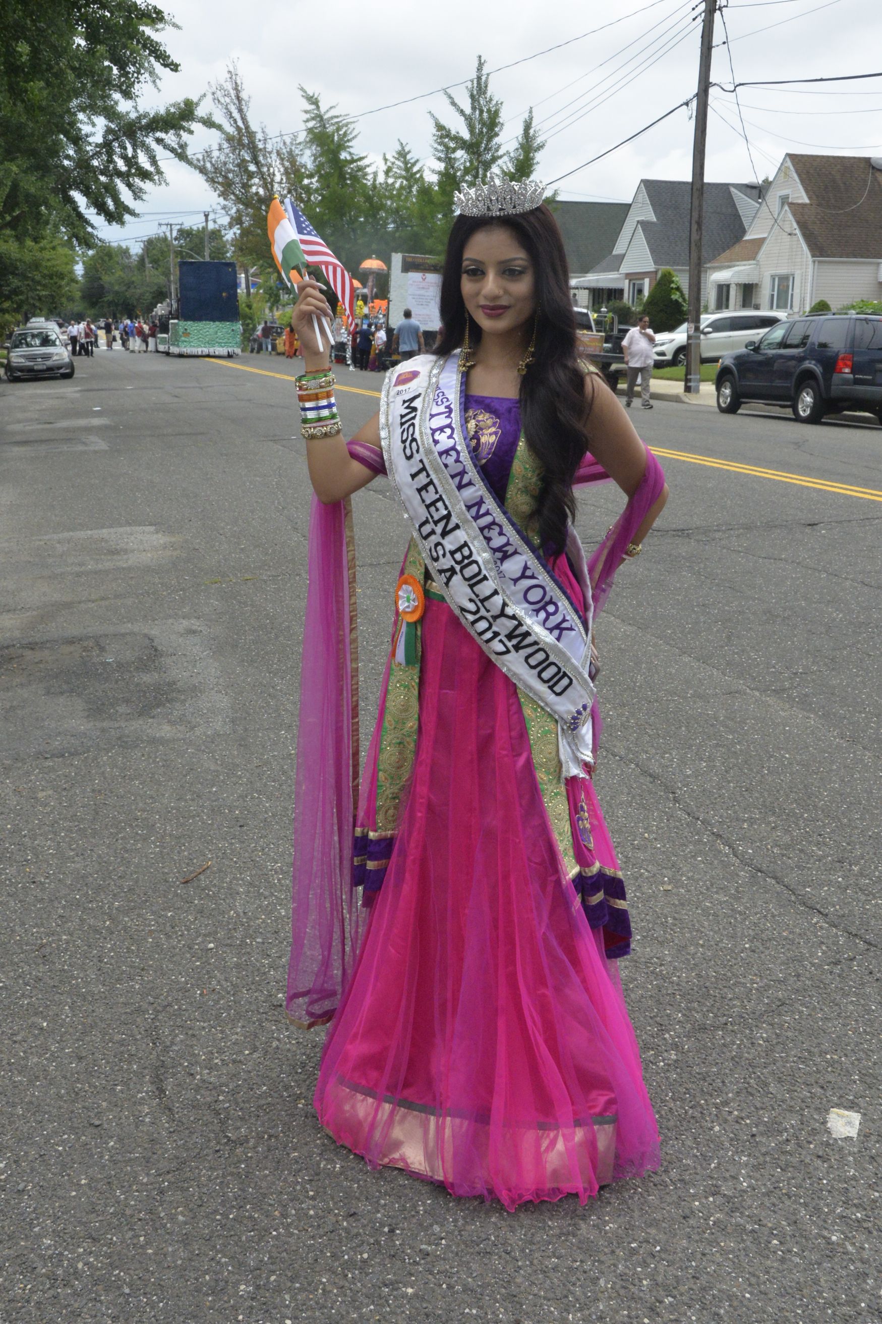 A woman in a pink dress is wearing a sash that says miss indian bollywood