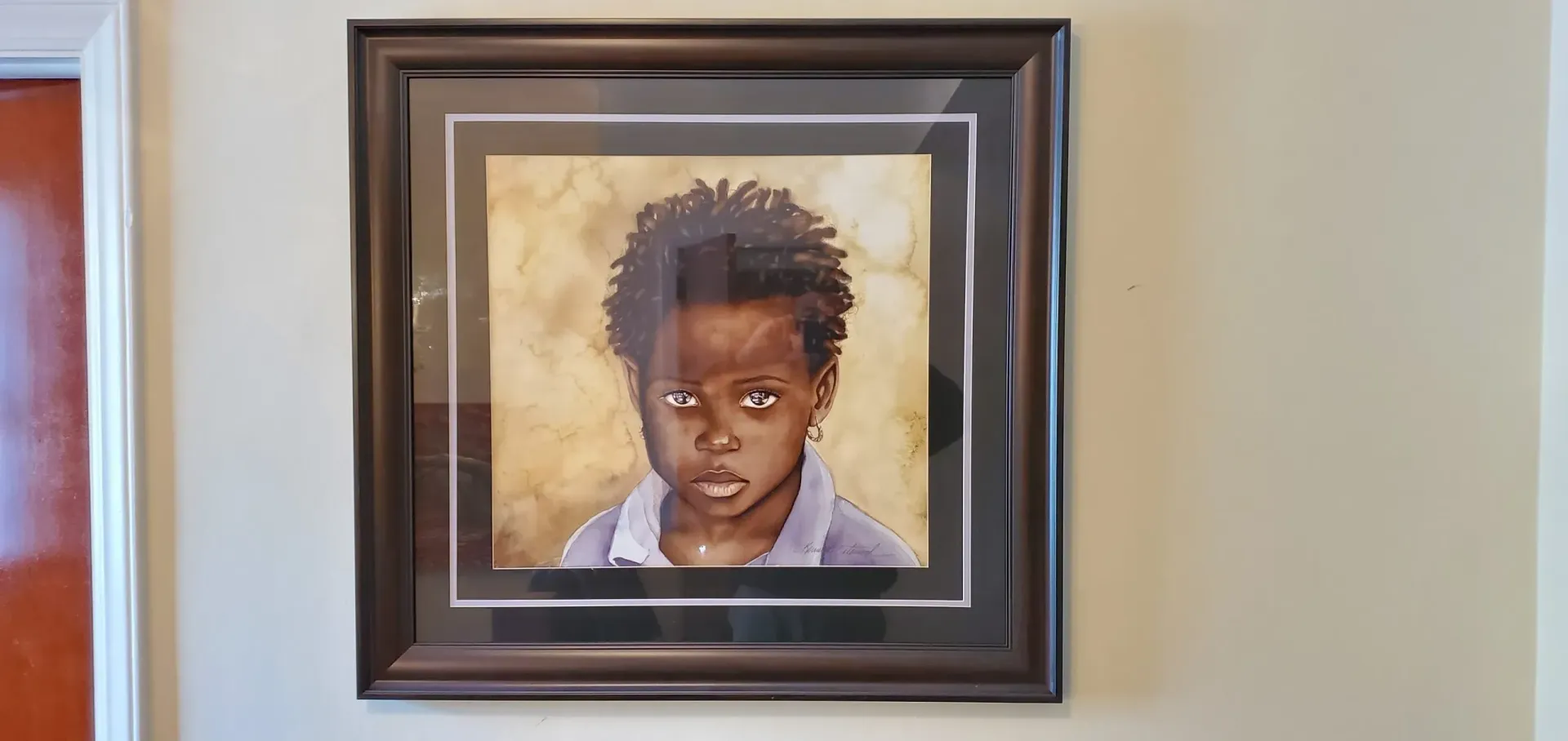 Framed portrait of a child with dark skin and curly hair, looking directly at the viewer.