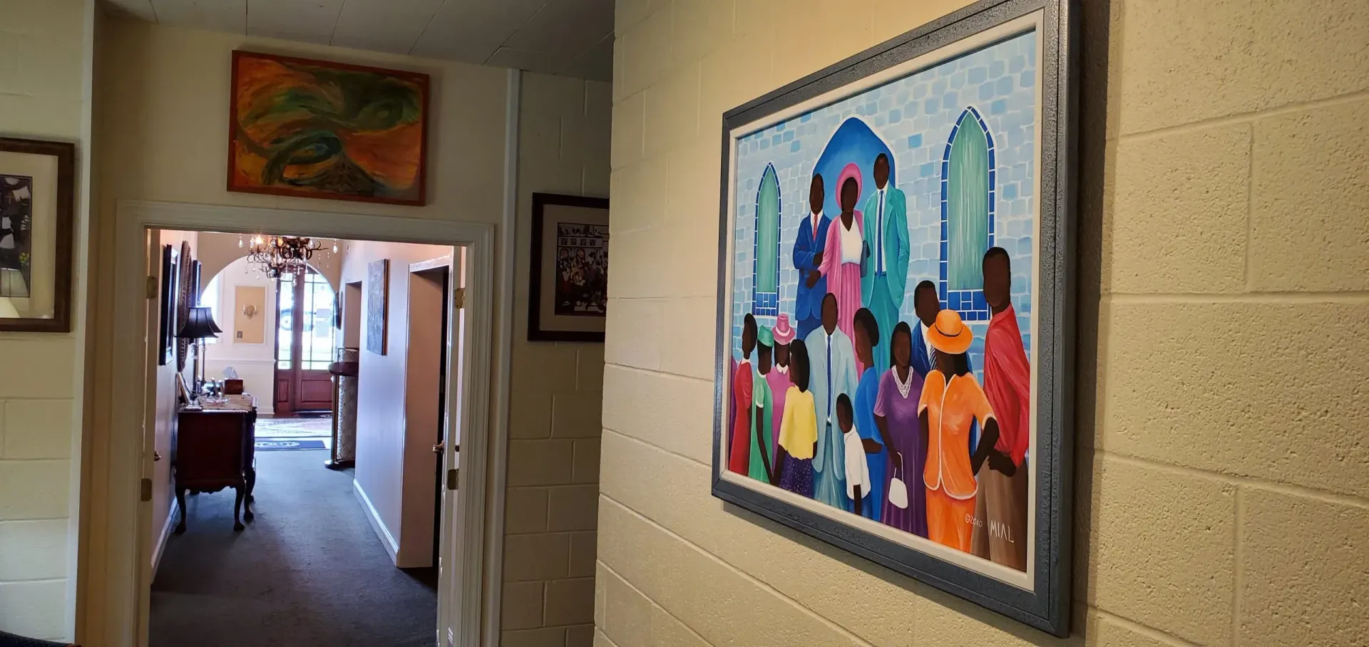 Hallway with artwork. A painting of people and an open door to another room.