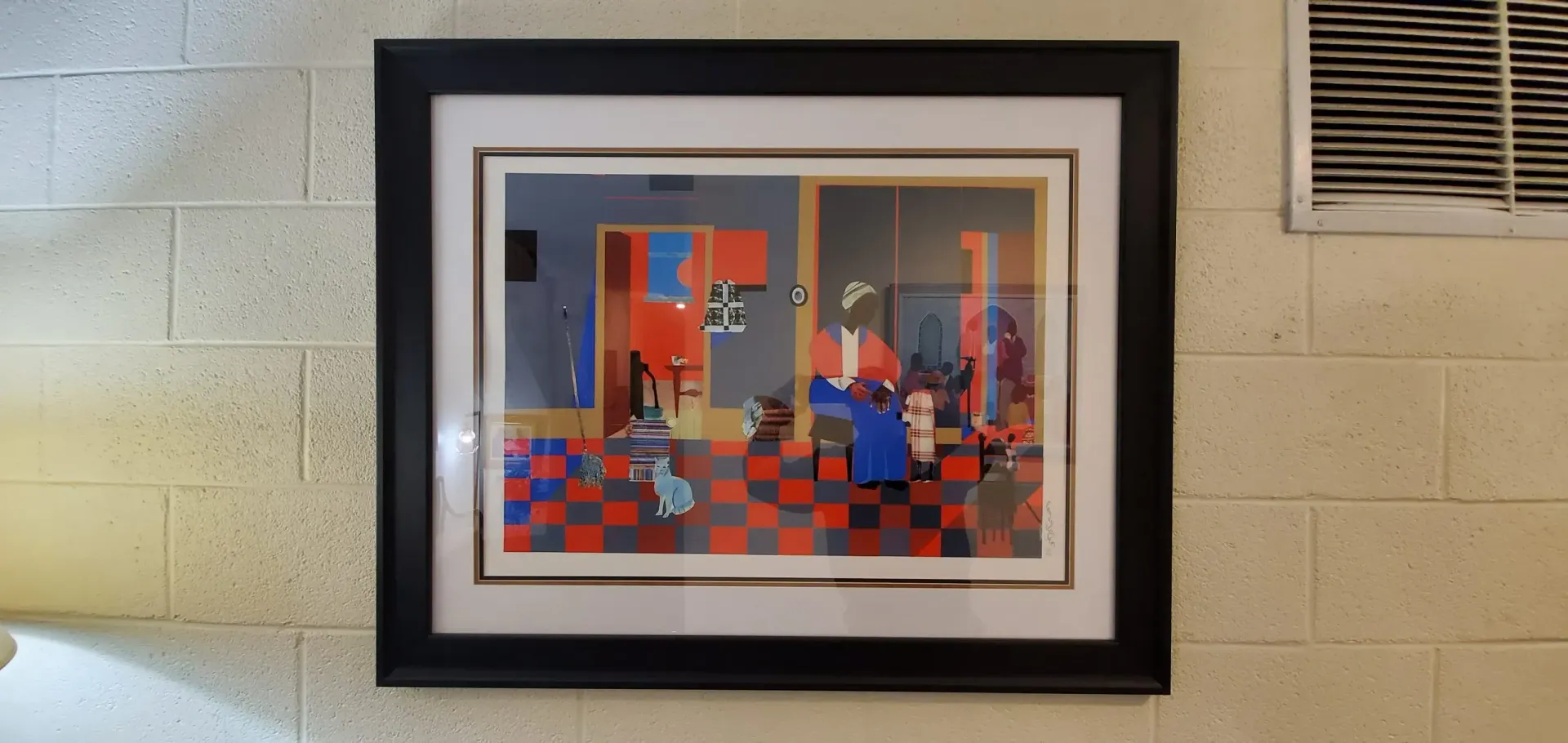 Framed artwork hangs on a light-colored brick wall. The art features a checkered floor and a room with figures.