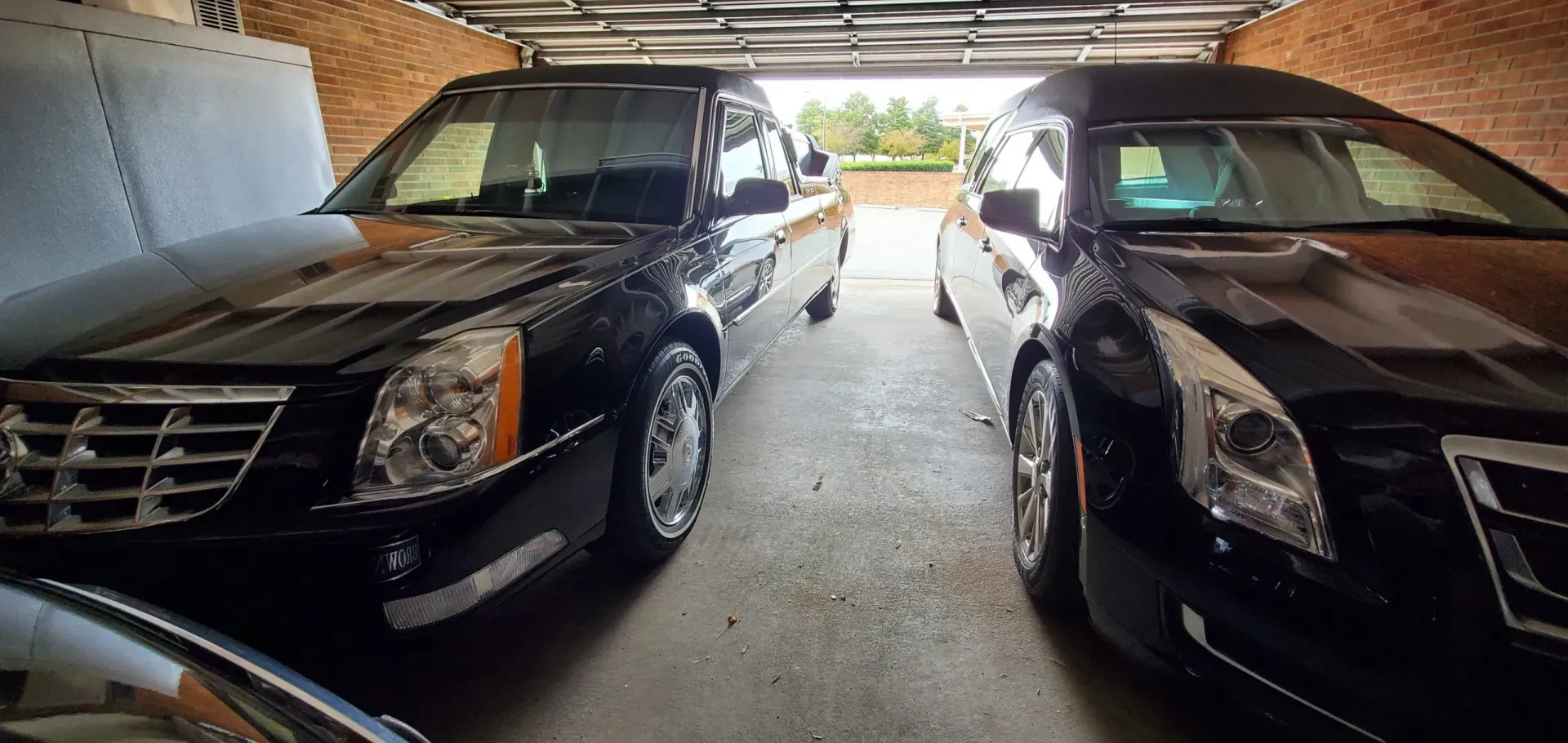 Two black hearses parked inside a garage.