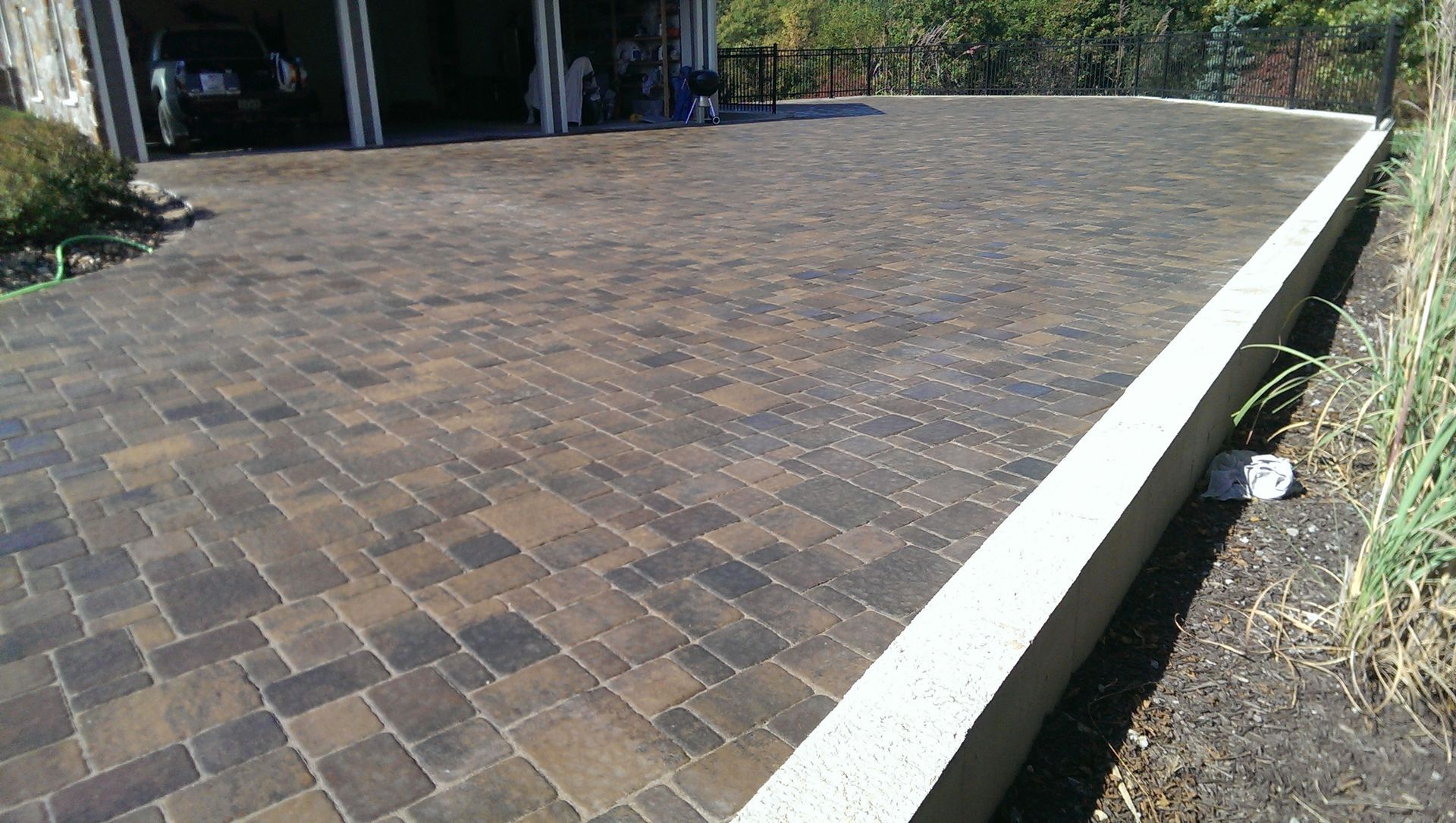 Brick paved driveway next to a concrete retaining wall, leading to garage.