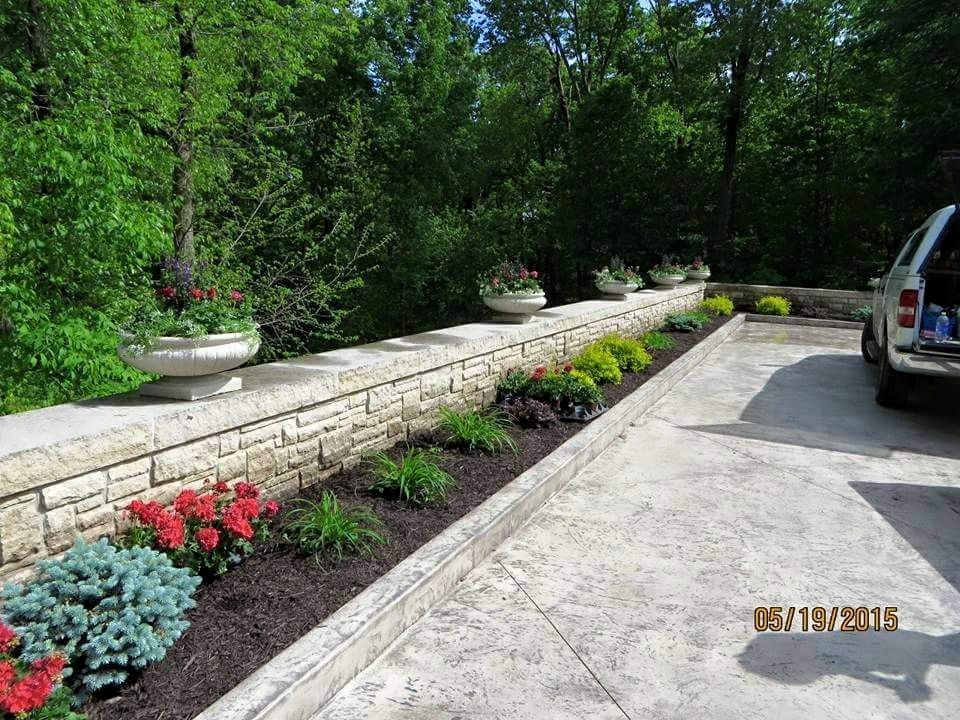 A car is parked in a driveway next to a stone wall.