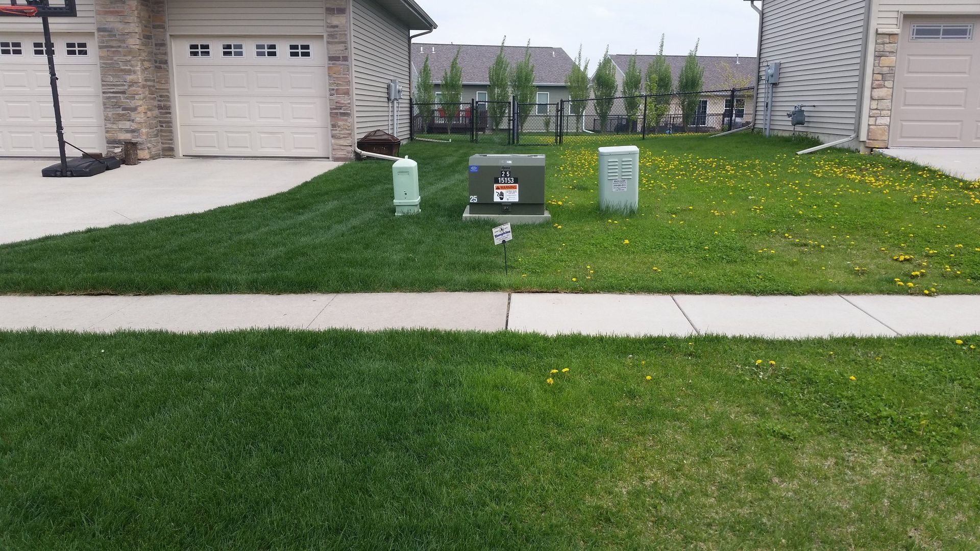 A lush green lawn with a concrete sidewalk in front of a house.