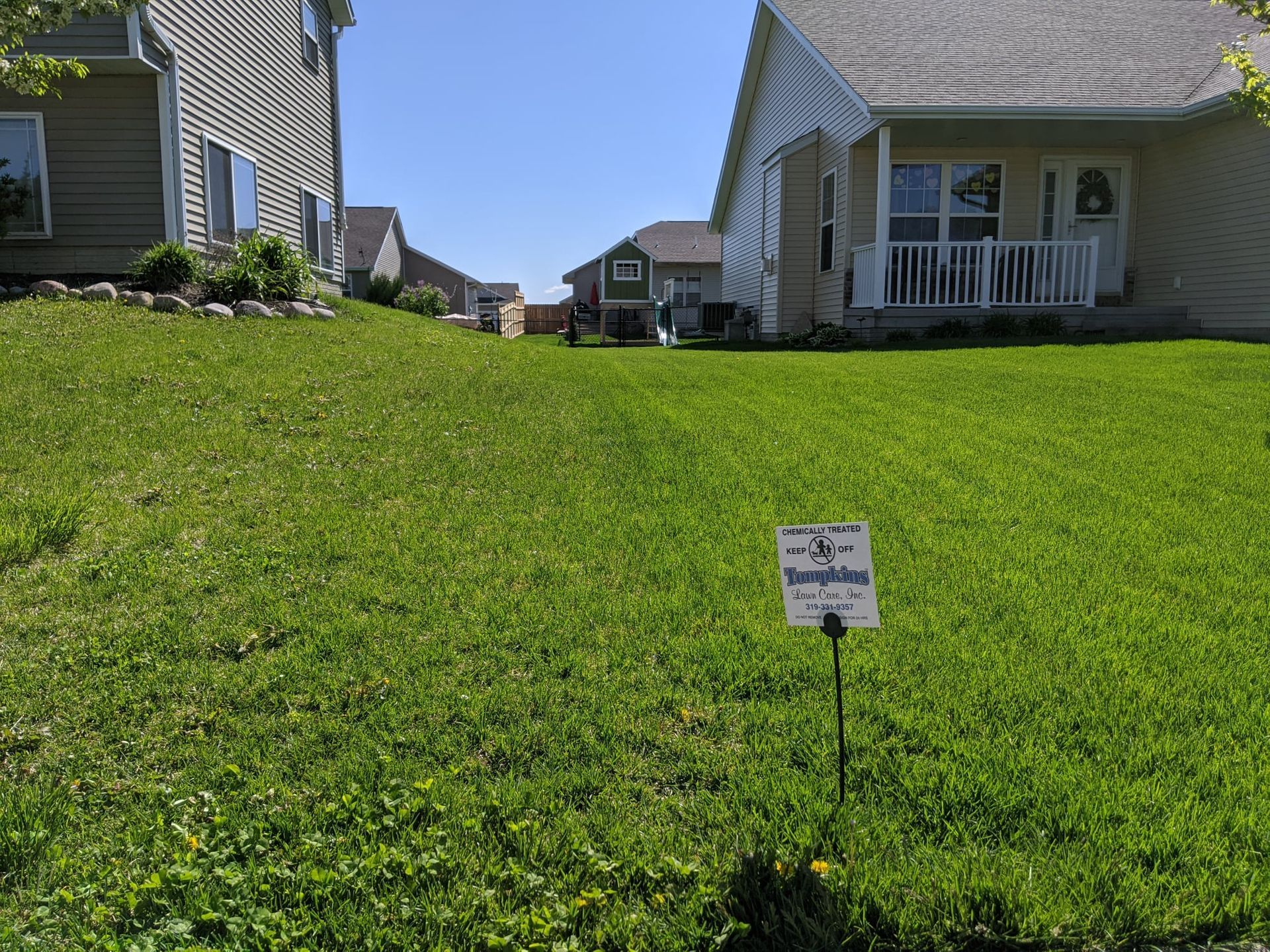 A lush green lawn with a sign in front of a house.