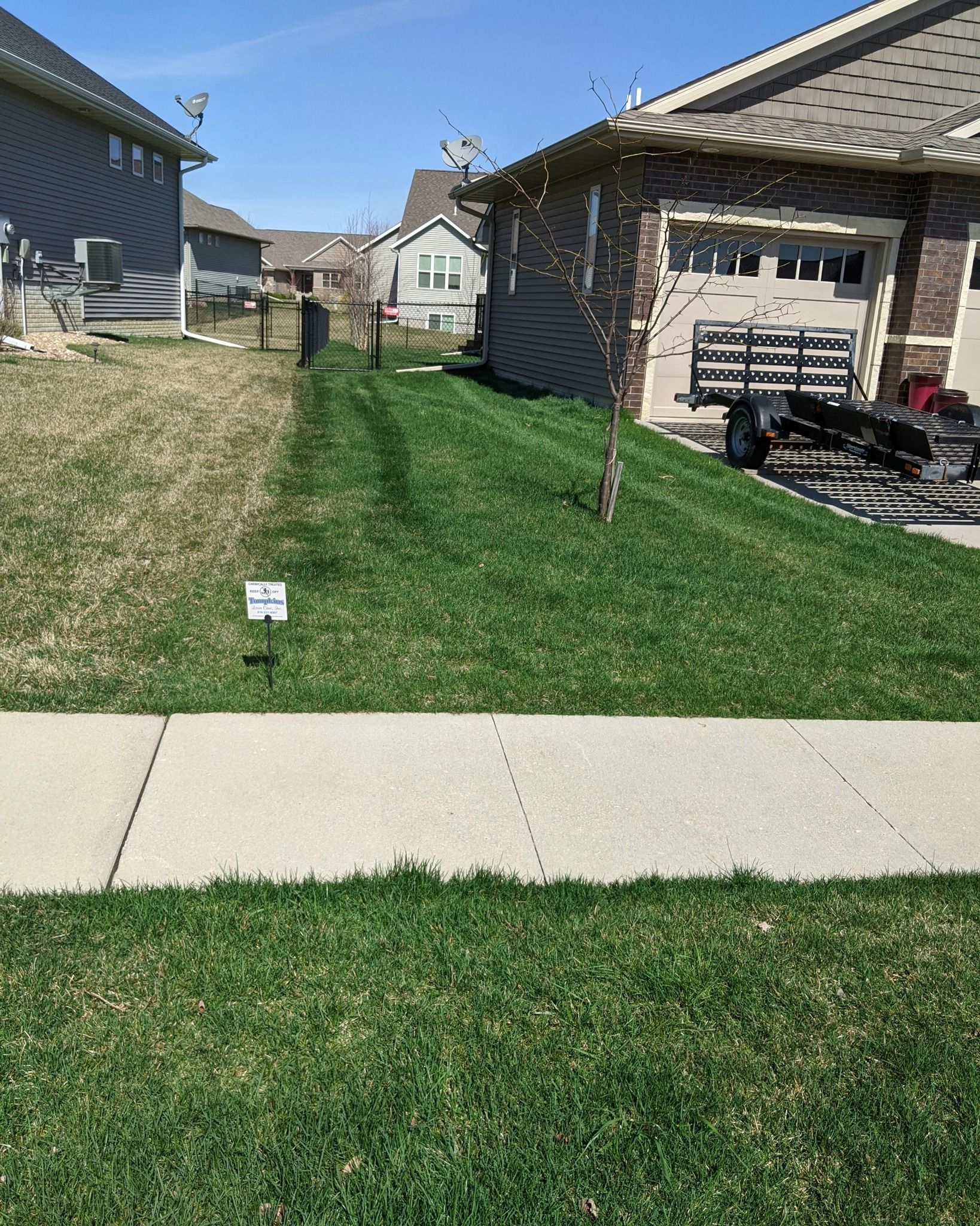 A sidewalk leading to a lush green lawn next to a house.