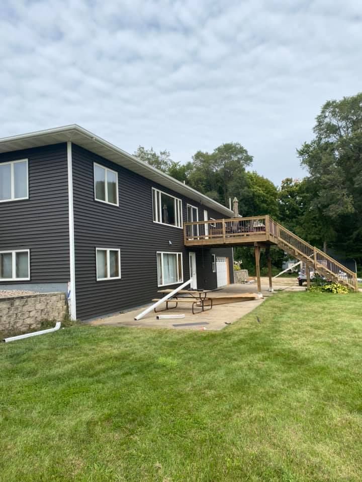 A large house with a deck and a picnic table in the backyard.