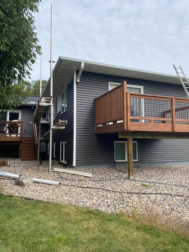 A house with a wooden deck and stairs is being painted.