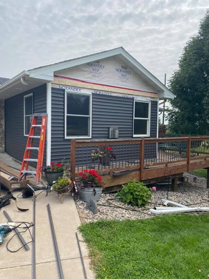 A small house with a deck and a ladder in front of it.