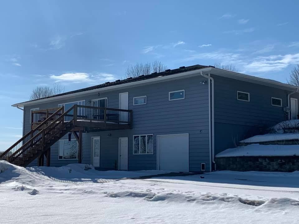 A large house with a balcony and stairs in the snow.