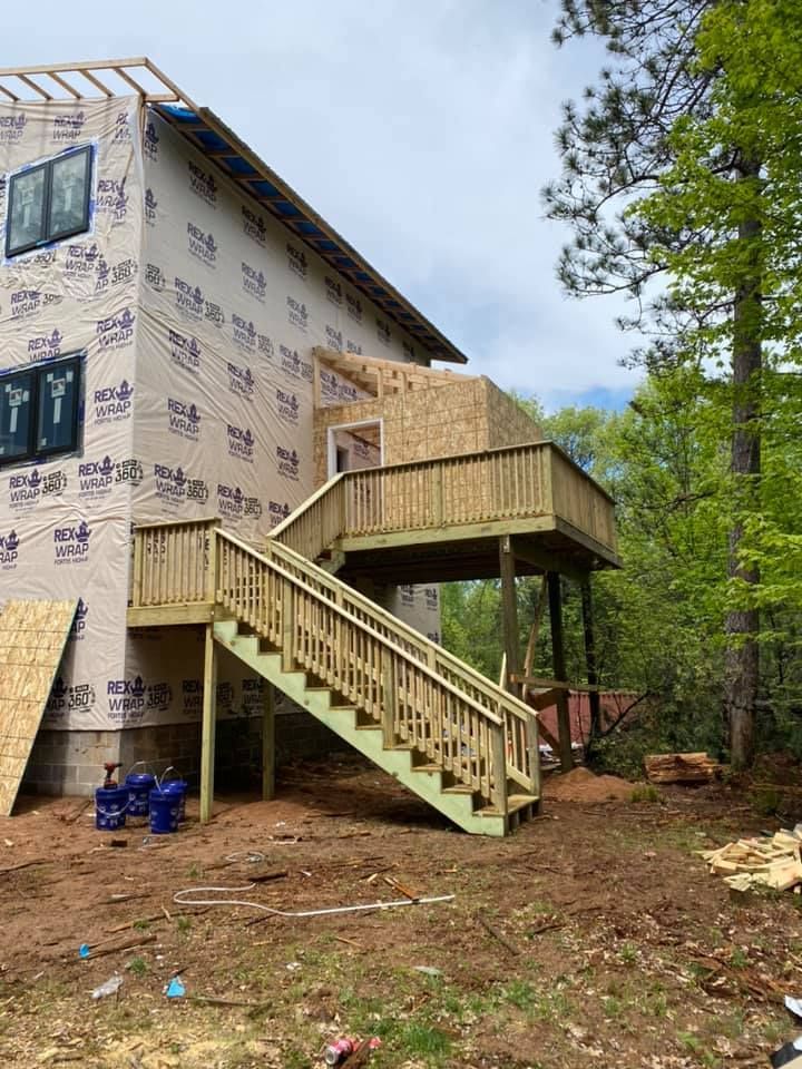 A house under construction with a wooden deck and stairs.