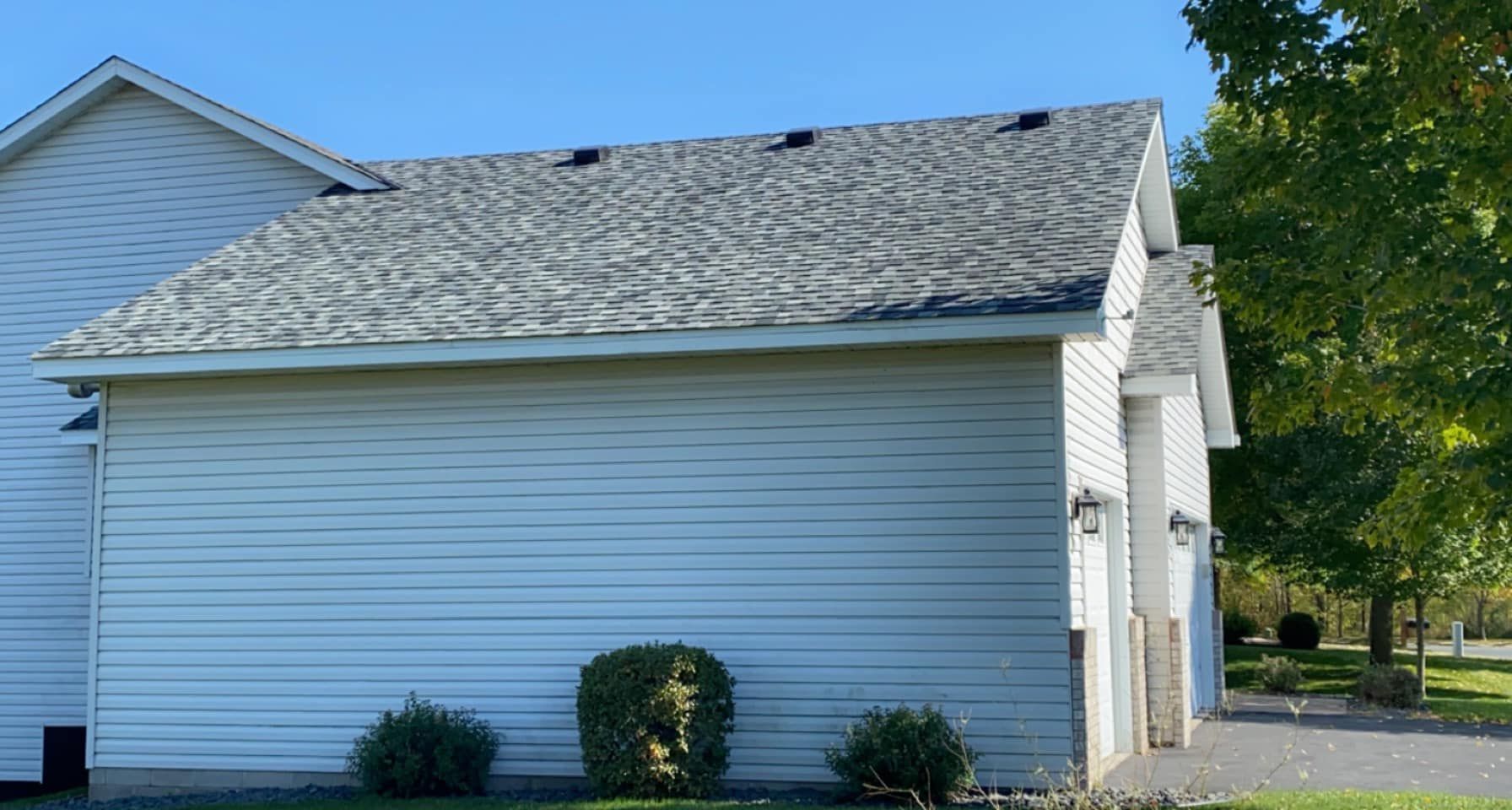A white house with a gray roof and a driveway.