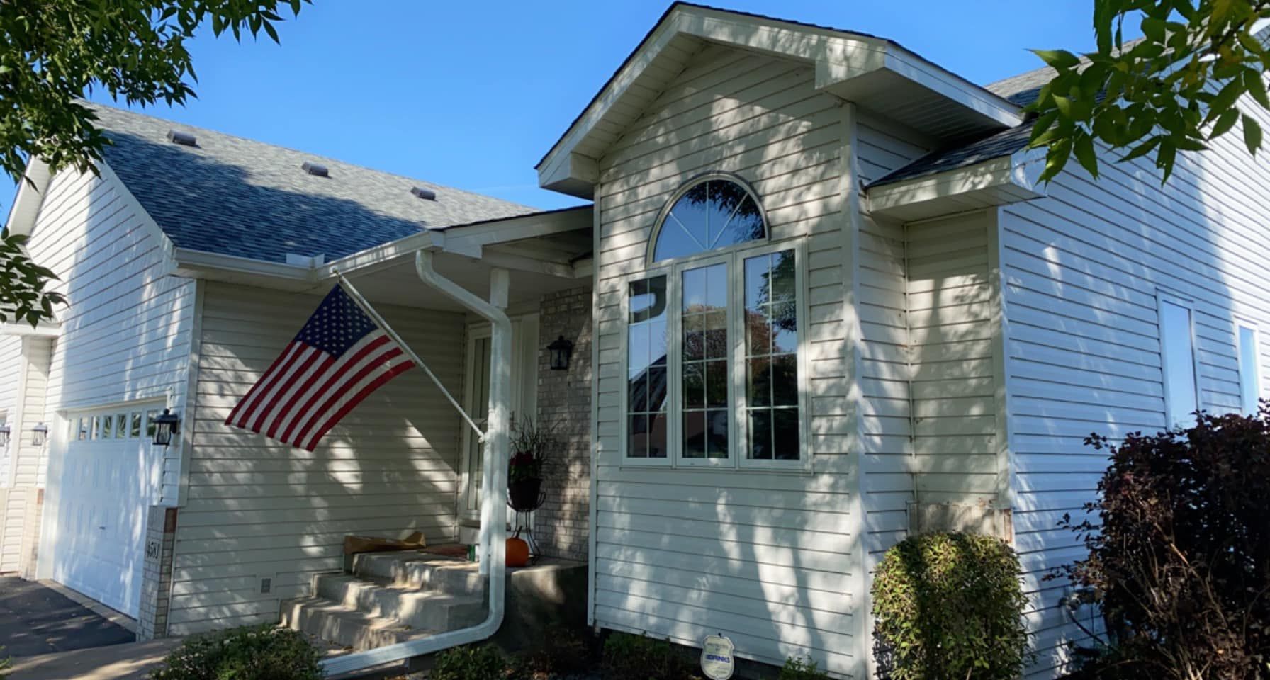 A white house with an american flag on the porch.