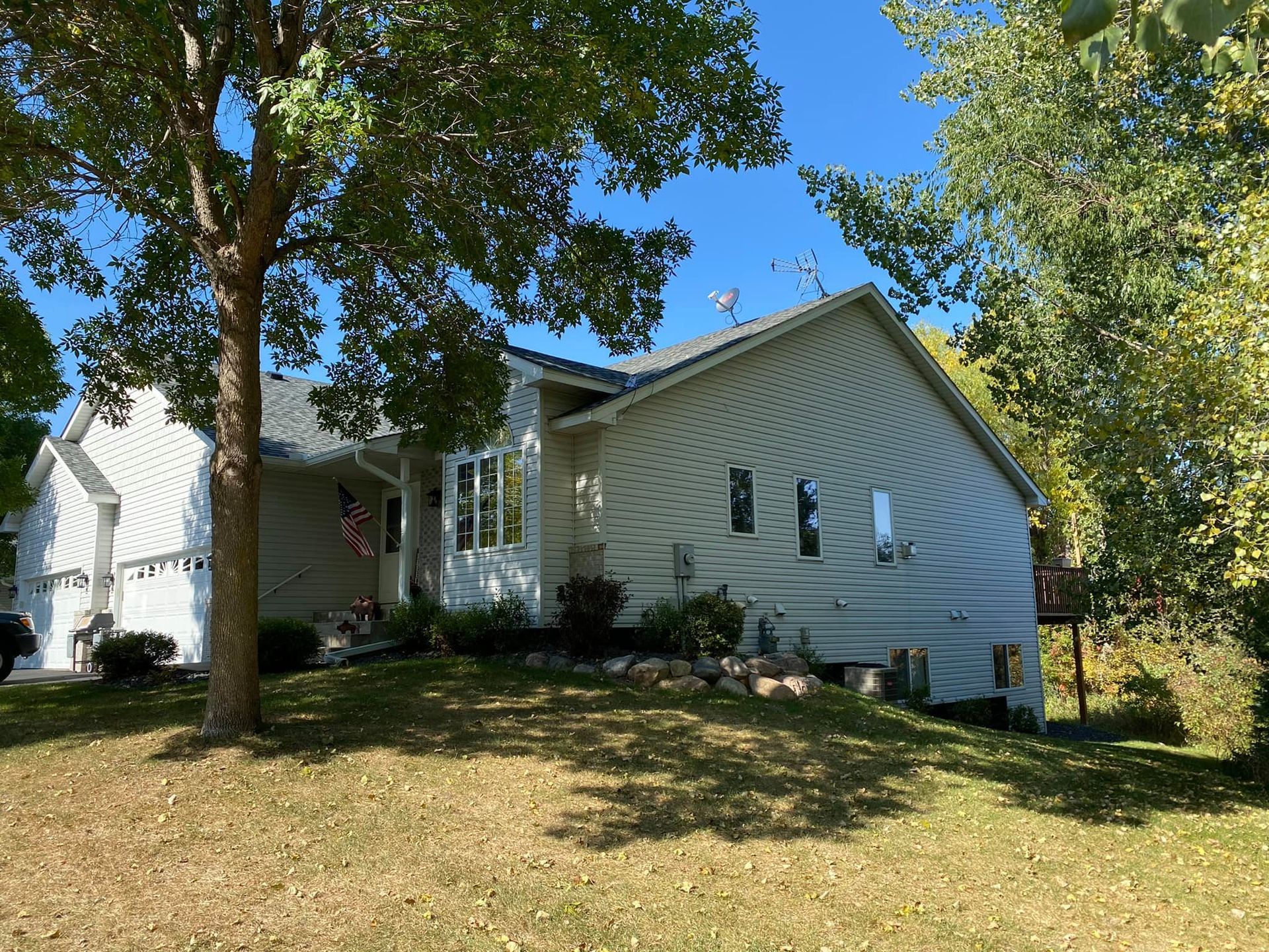 A white house is sitting on top of a grassy hill surrounded by trees.