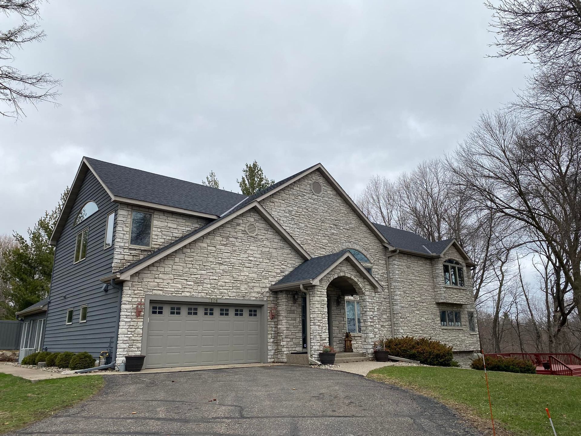 A large stone house with a garage and a driveway leading to it.