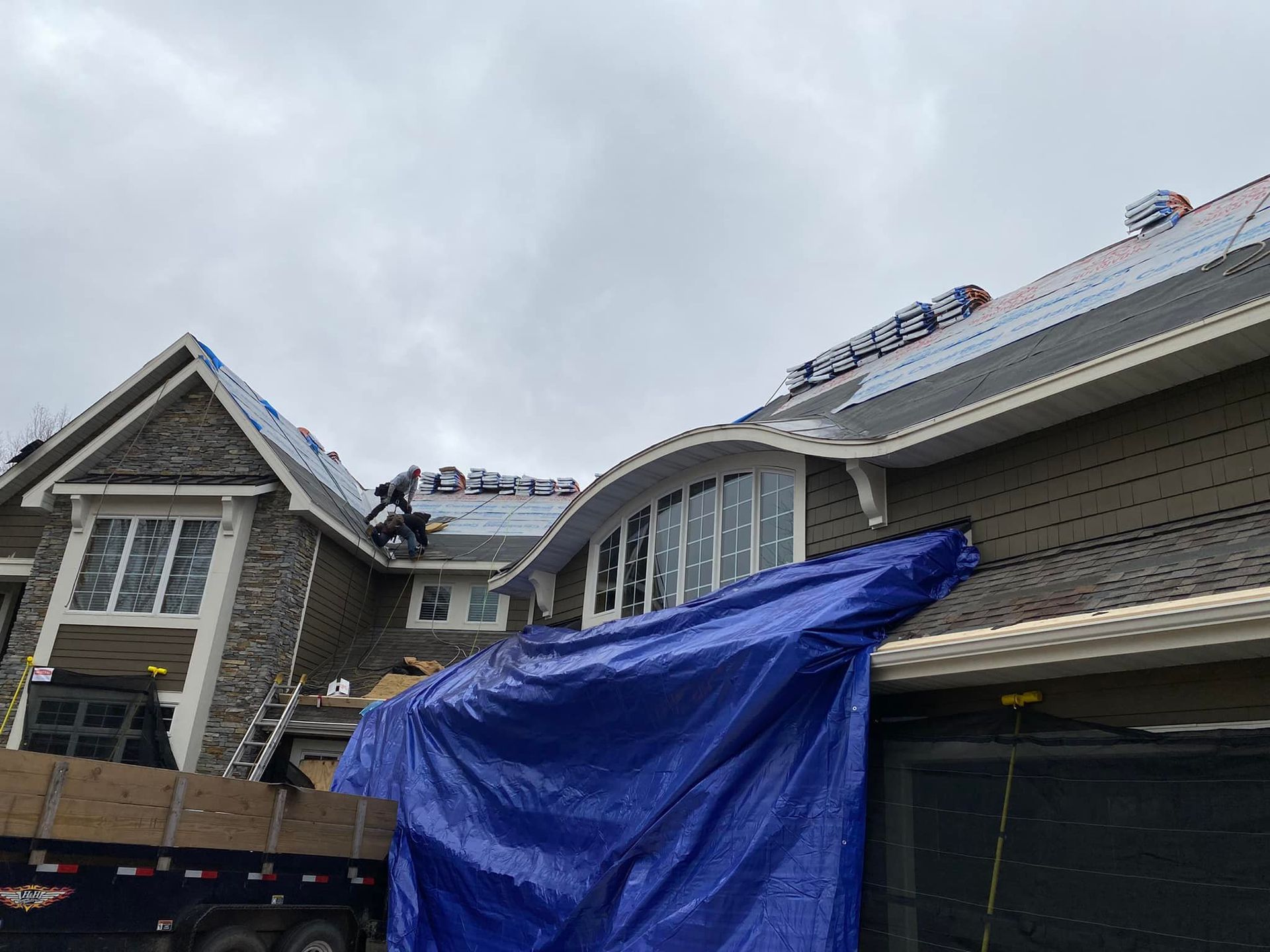 A large house with a blue tarp on the side of it.
