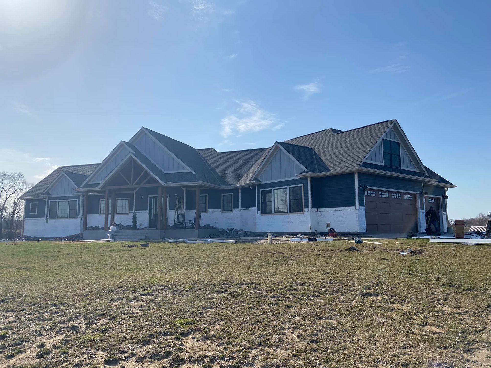 A large house is being built in the middle of a grassy field.