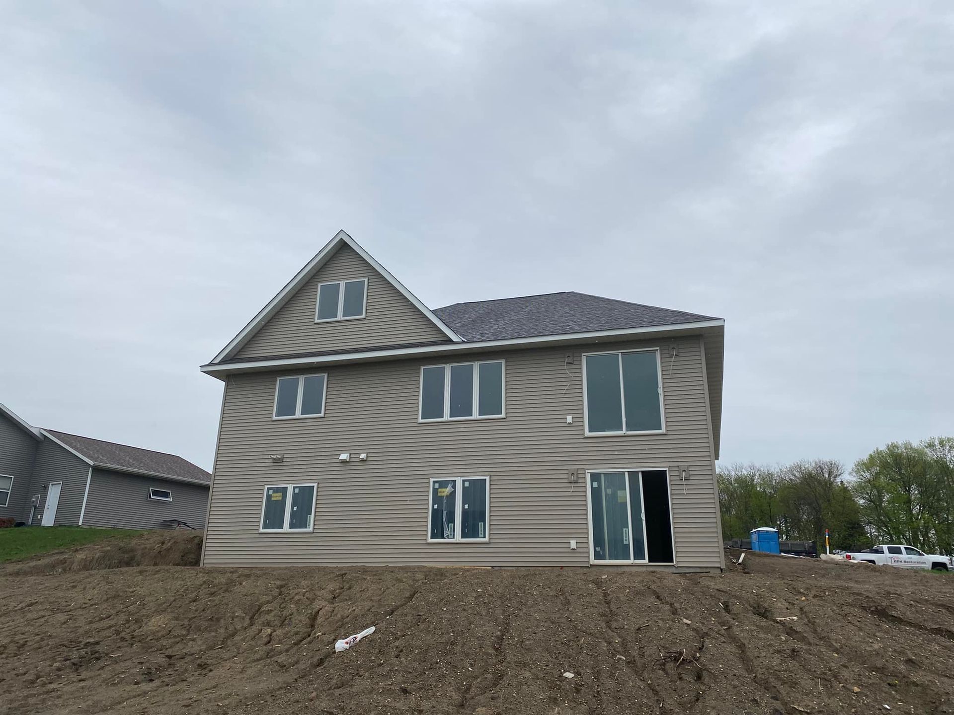 A large house is sitting on top of a dirt hill.