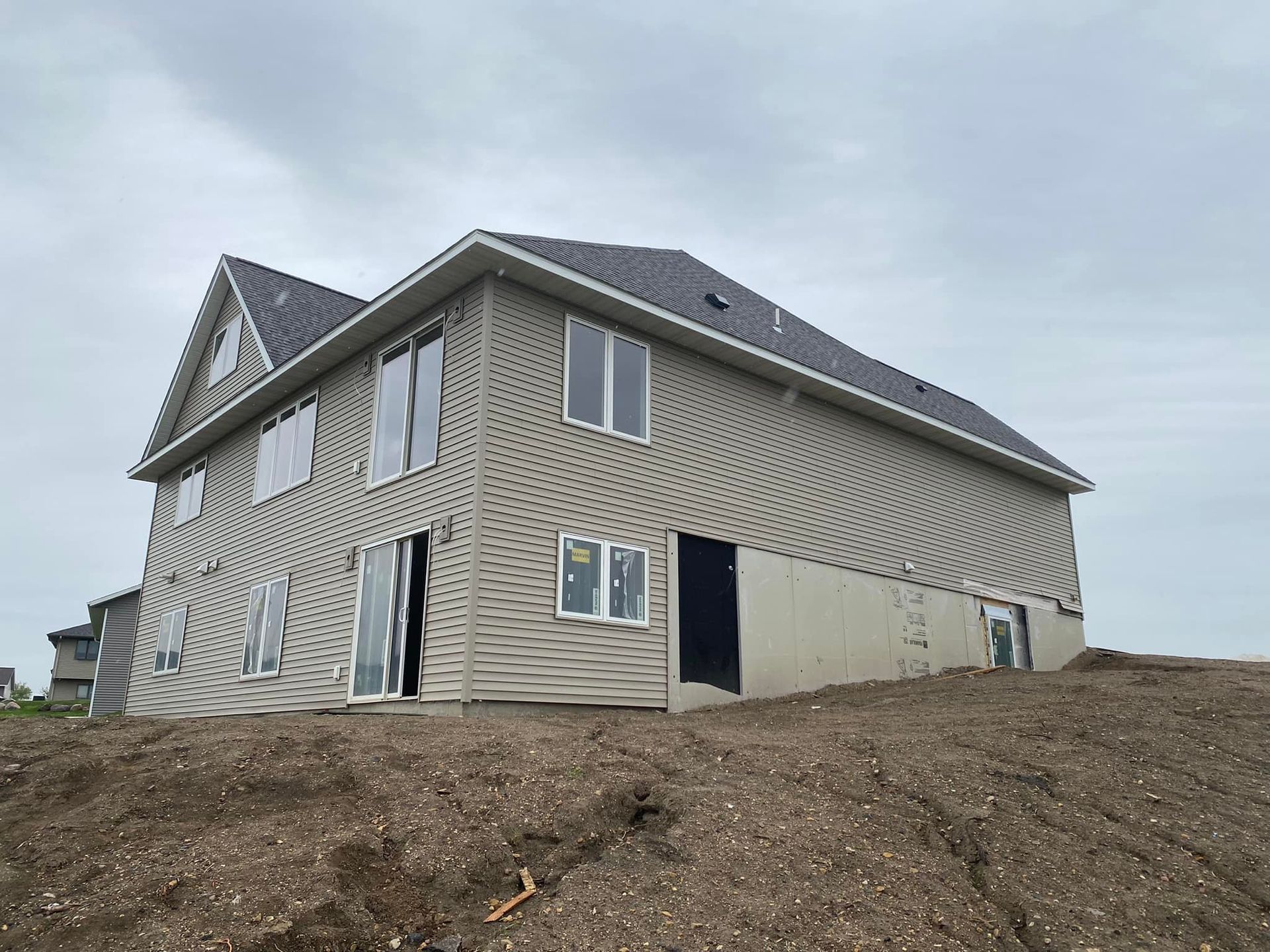 A large house is sitting on top of a dirt hill.