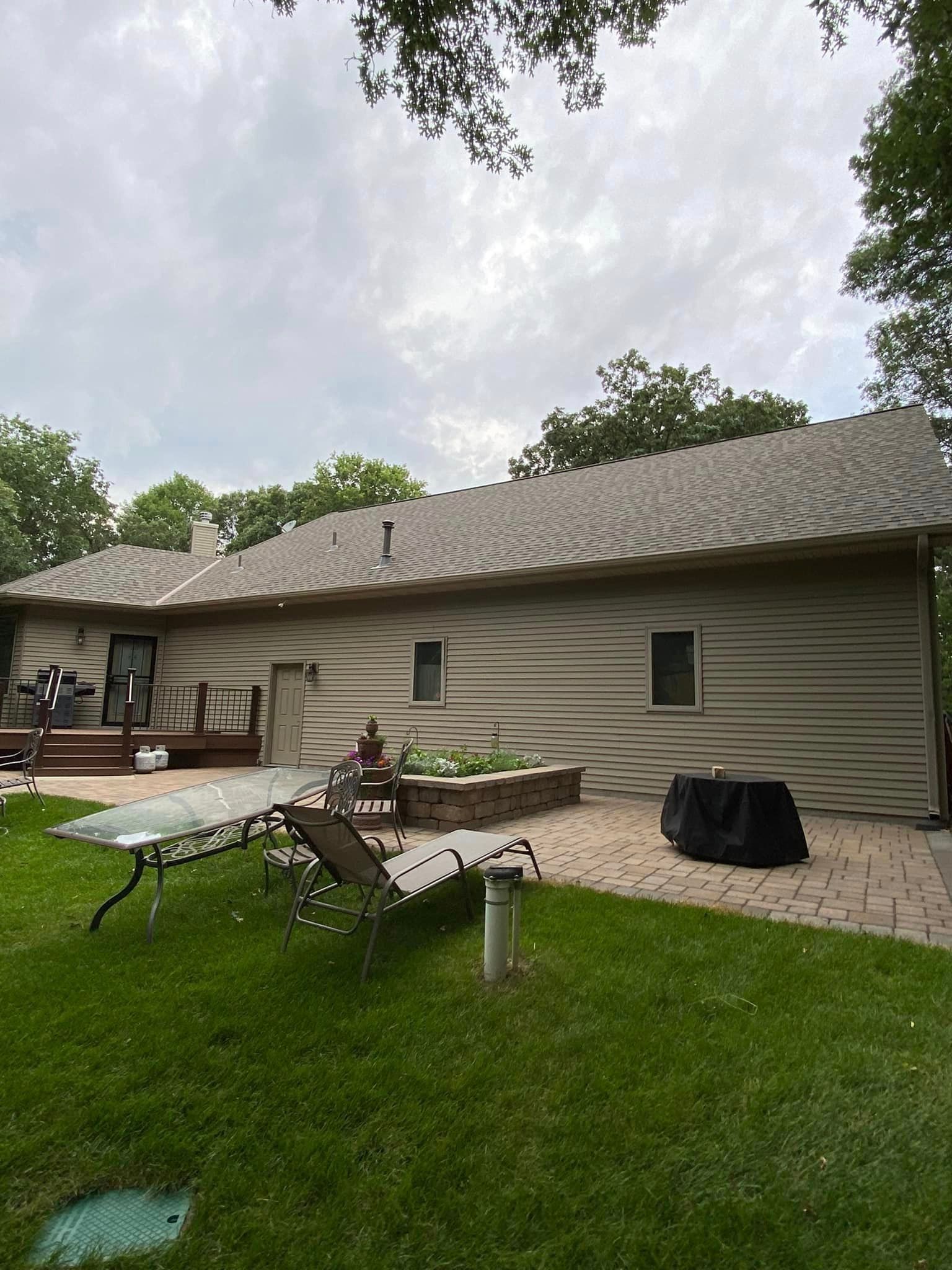 The backyard of a house with a table and chairs in the grass.