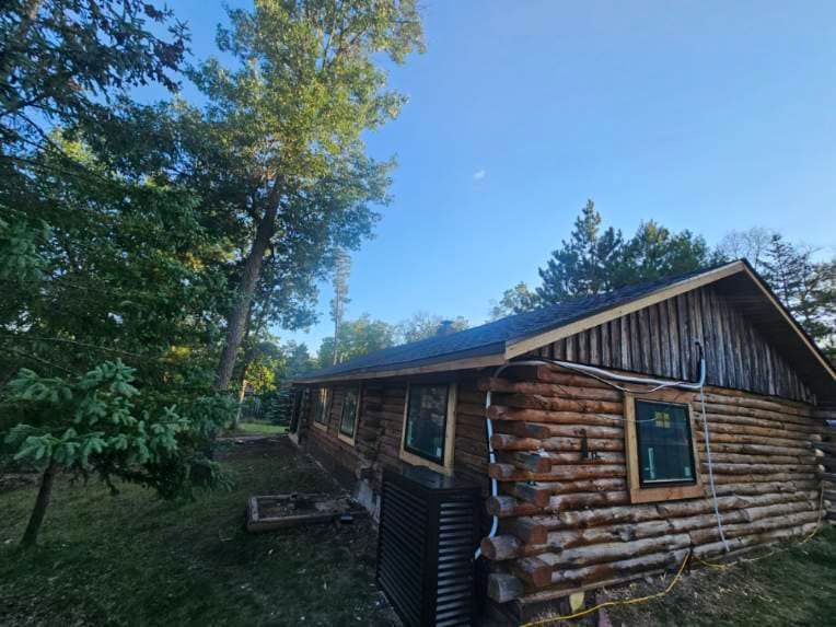 A log cabin is sitting in the middle of a forest surrounded by trees.