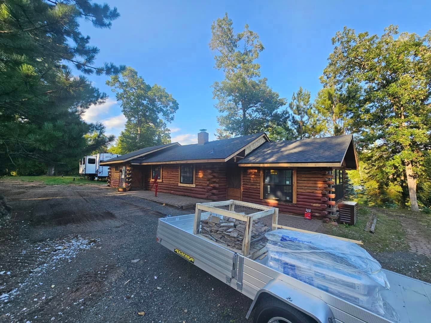 A trailer is parked in front of a log cabin.