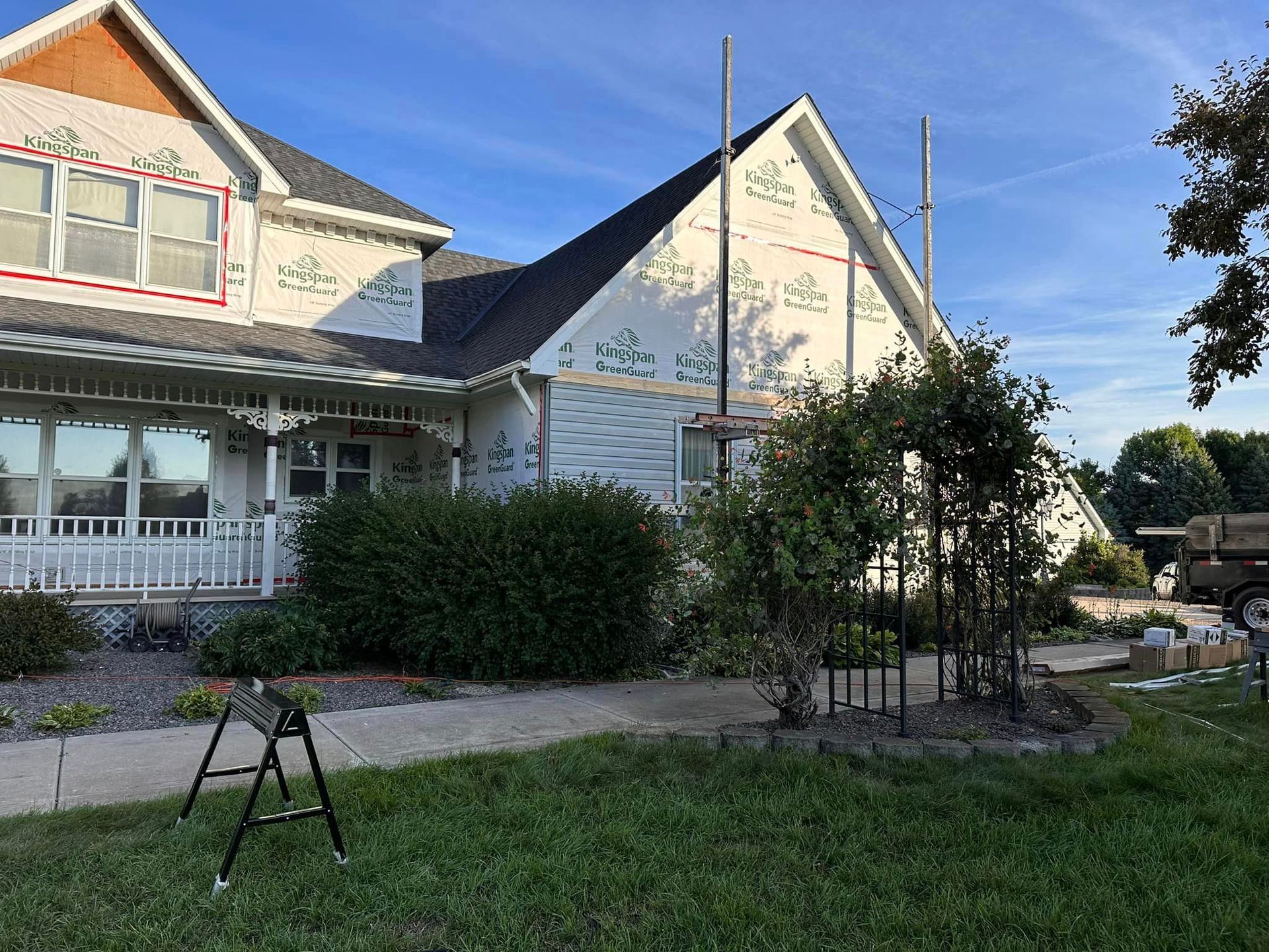 A large white house is being built with a truck parked in front of it.