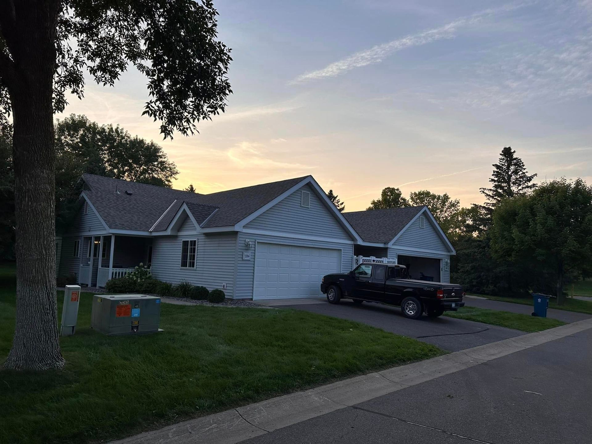 A black truck is parked in front of a white house.