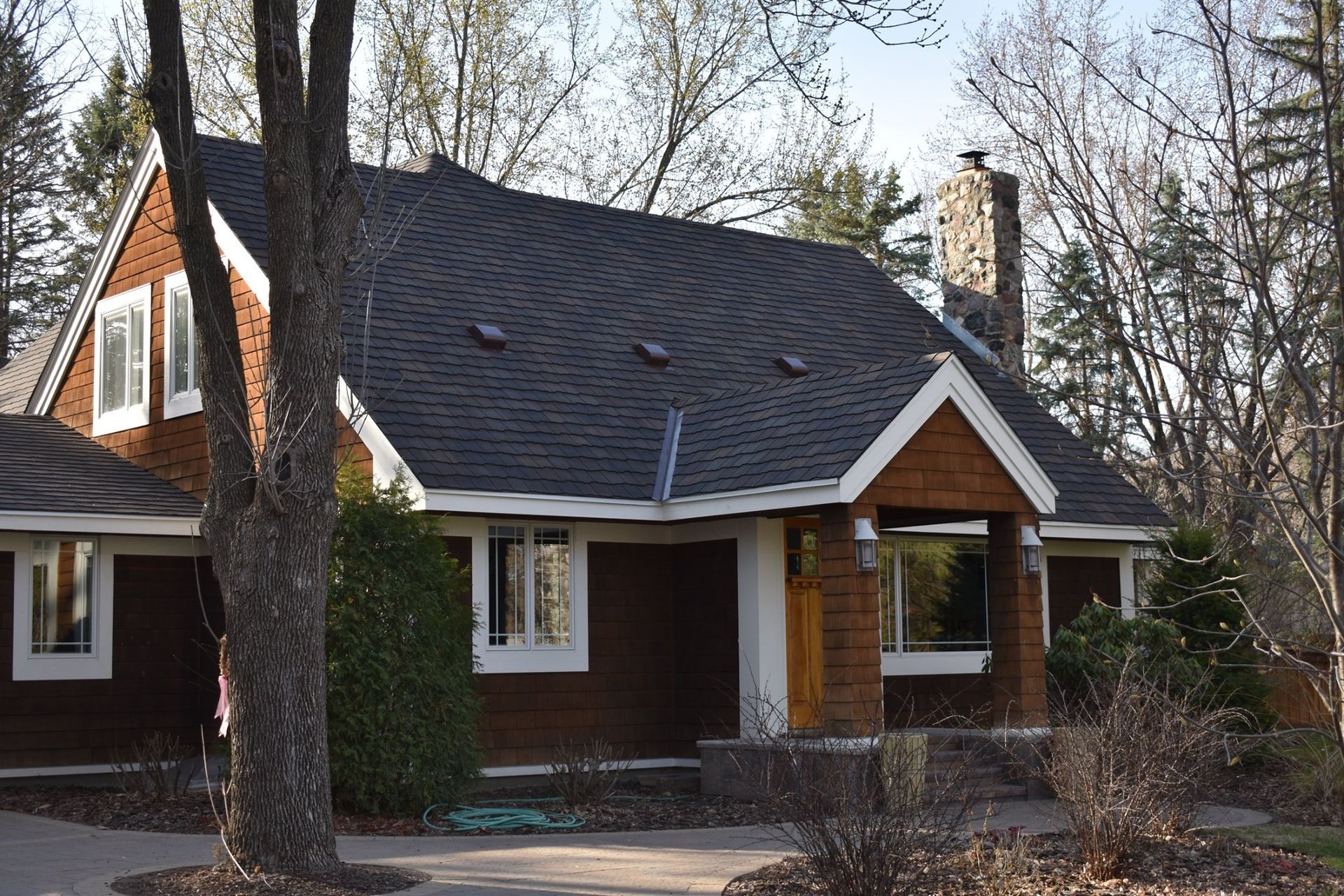 A house with a black roof is surrounded by trees