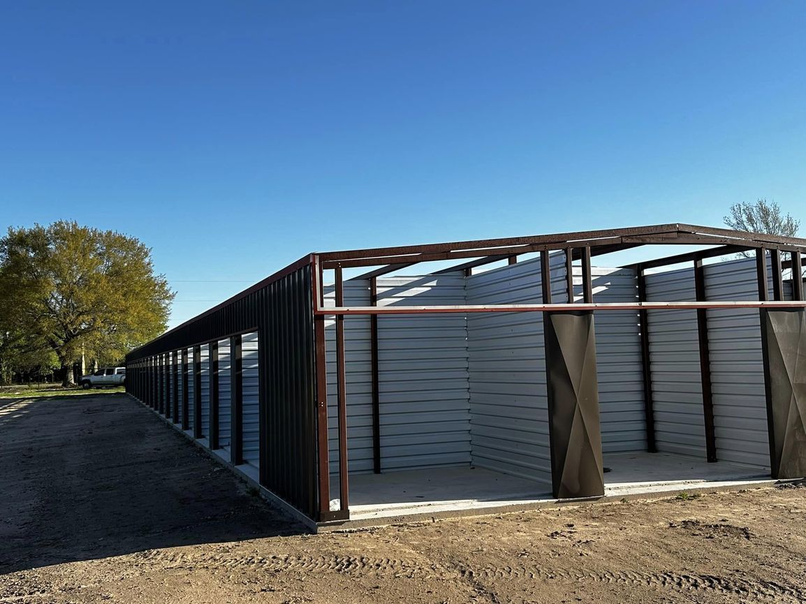 Long metal shed with open bays under a blue sky.