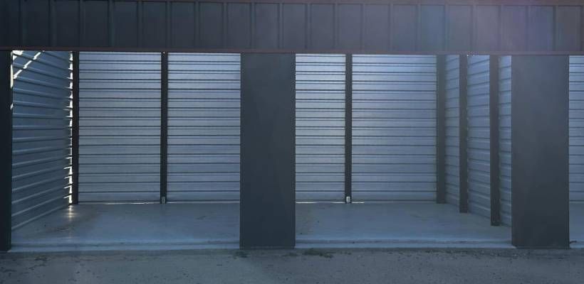 Architectural detail: metal structure with horizontal slats, pillars, and open space, bathed in sunlight.
