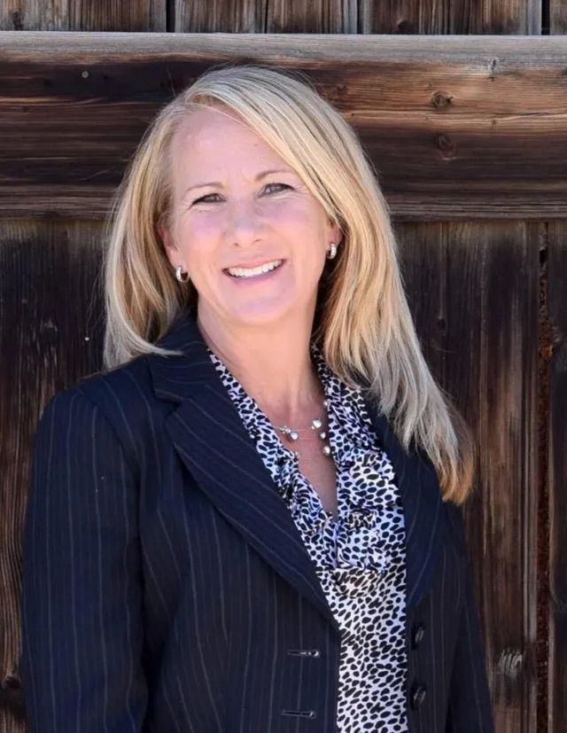 A woman in a black jacket is smiling for the camera.
