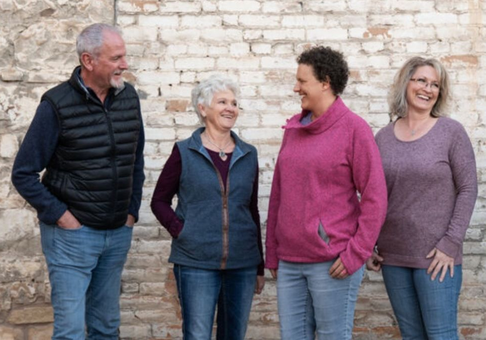A group of people are standing next to each other in front of a brick wall.