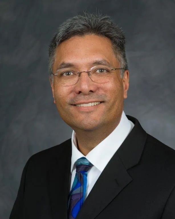 A man in a suit and tie is smiling for the camera
