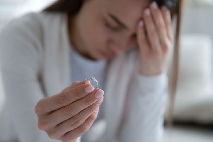 Une personne est assise sur une chaise avec les mains jointes en réflexion.