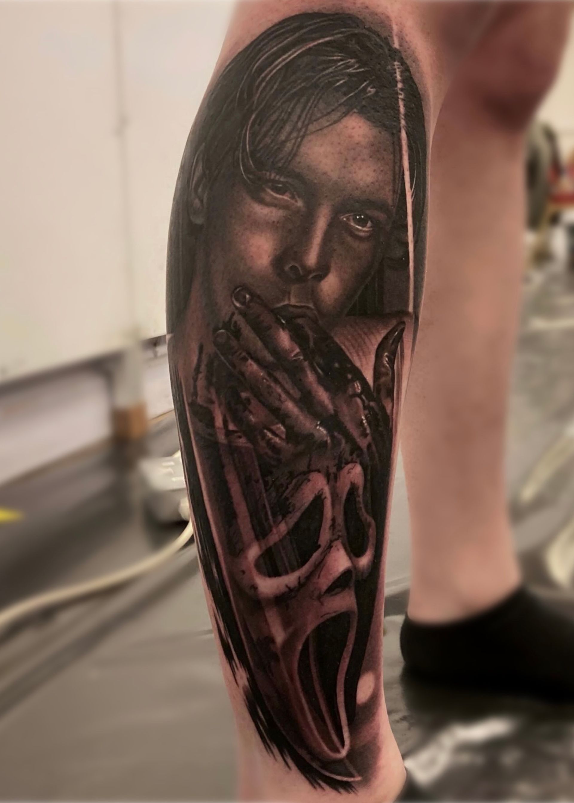 A tattoo of a woman with a scream mask on her leg