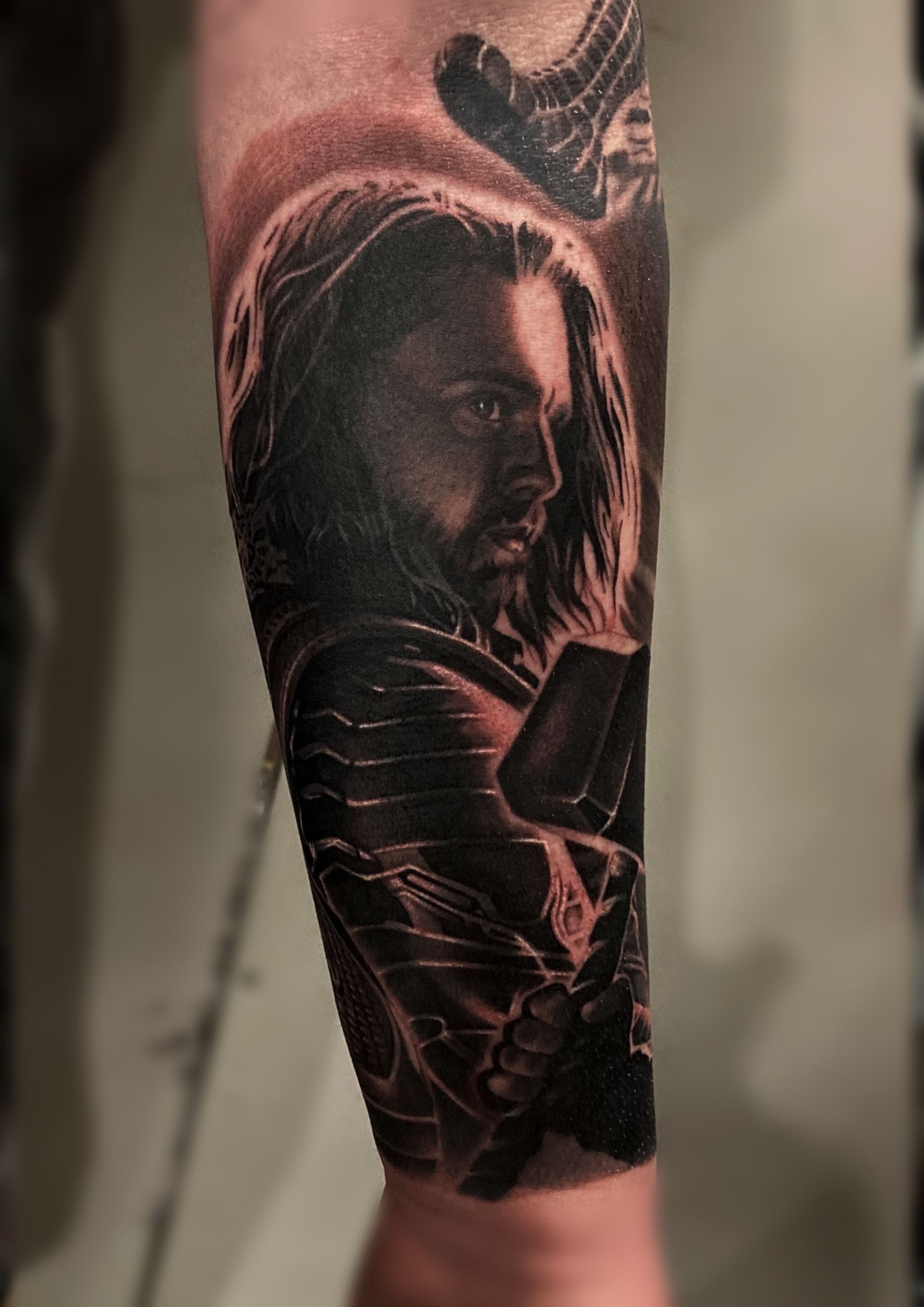 A black and white tattoo of a man with long hair and a beard on his arm.