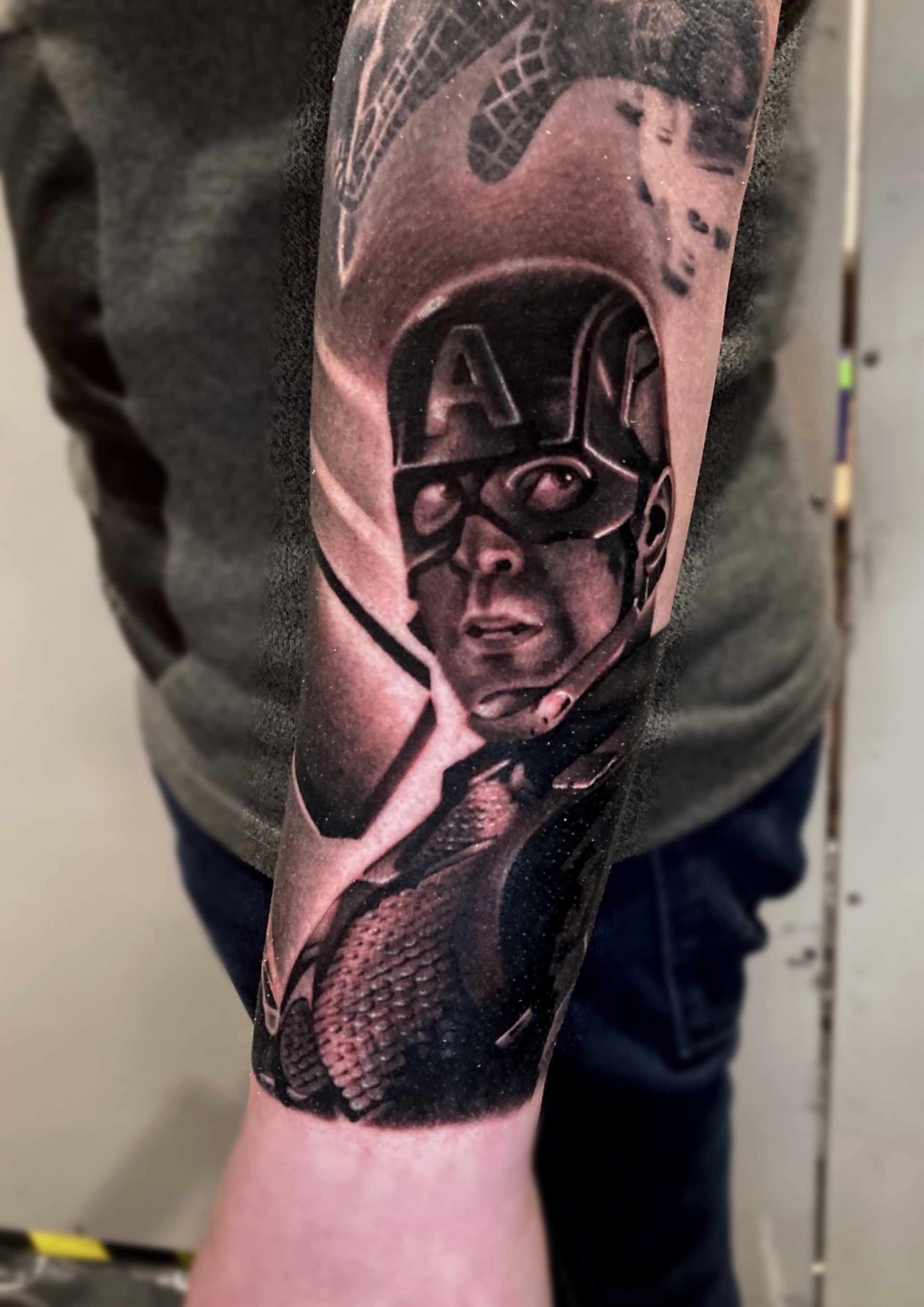 A man has a tattoo of captain america on his arm
