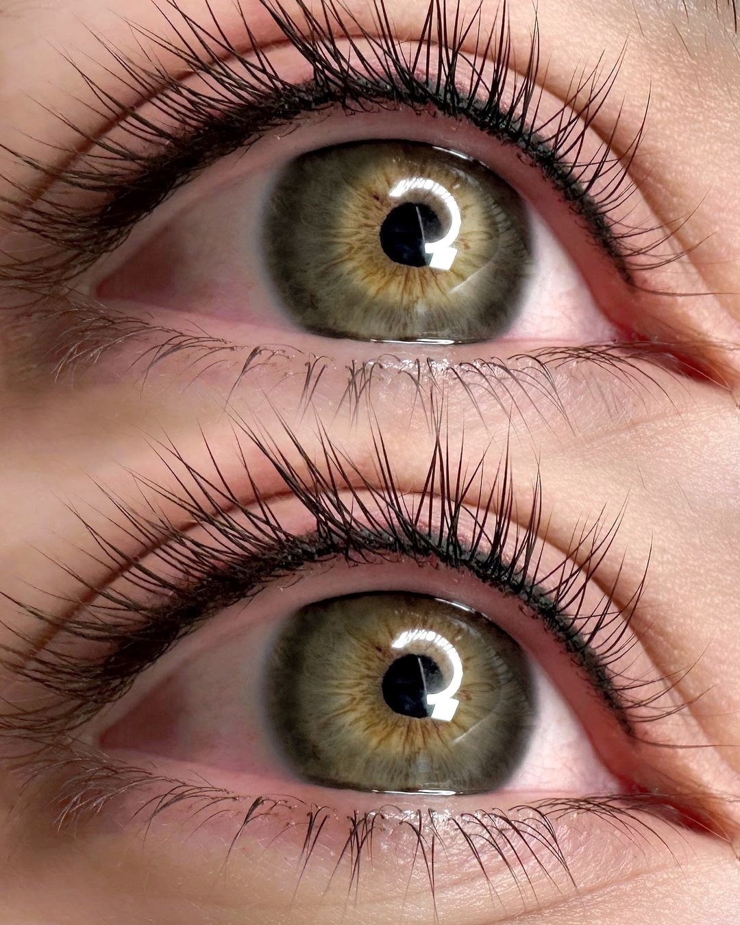A close up of a woman 's green eyes with long eyelashes.